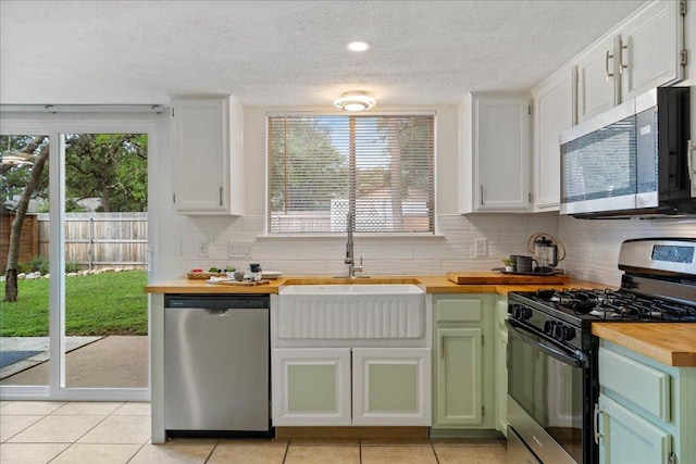 kitchen with backsplash, wooden counters, a textured ceiling, appliances with stainless steel finishes, and a sink