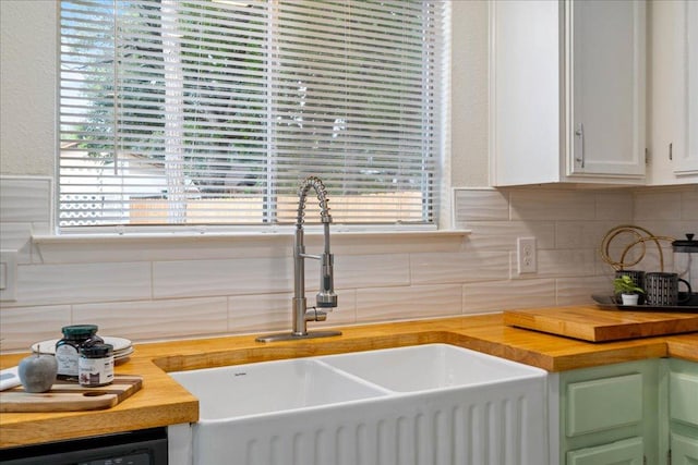 room details featuring a sink, wood counters, white cabinetry, and tasteful backsplash
