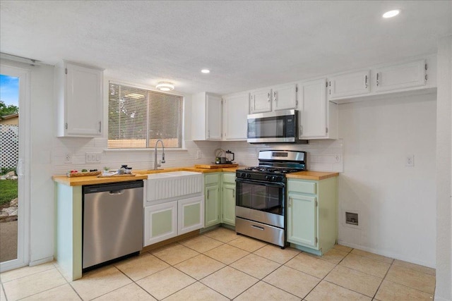 kitchen featuring white cabinetry, wood counters, appliances with stainless steel finishes, and decorative backsplash