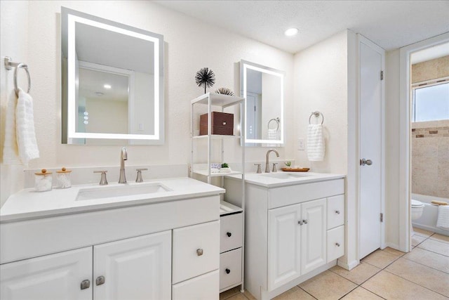 bathroom featuring toilet, tile patterned floors, two vanities, and a sink