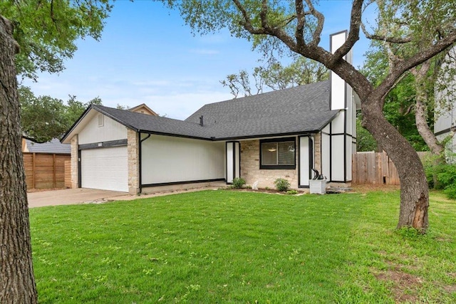 view of front of property featuring a garage, fence, a front yard, roof with shingles, and concrete driveway