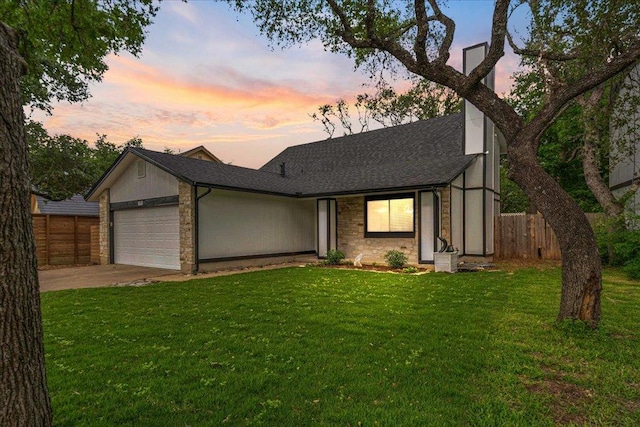 view of front of property with a garage, fence, stone siding, a front yard, and a shingled roof