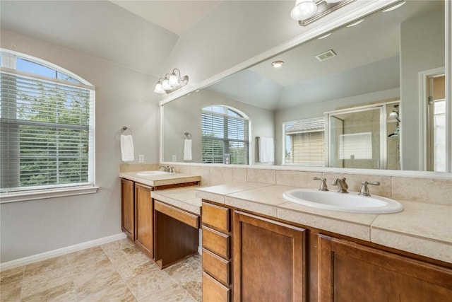 bathroom with a sink, a shower stall, double vanity, and visible vents