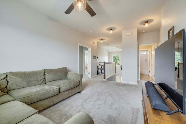carpeted living room with ceiling fan and baseboards