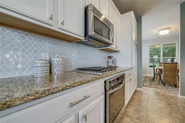 kitchen with decorative backsplash, light stone countertops, white cabinetry, appliances with stainless steel finishes, and light tile patterned floors