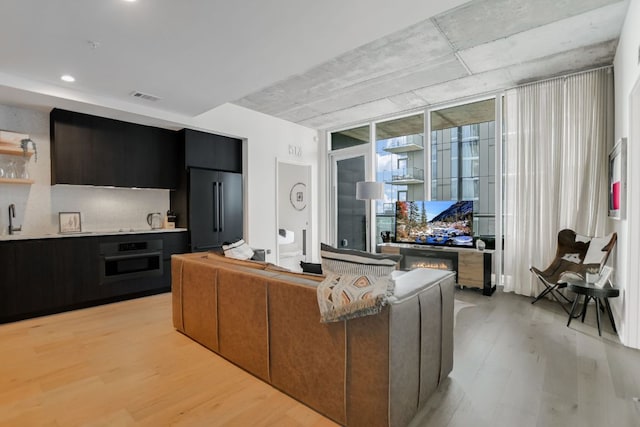 living area with visible vents, expansive windows, and light wood finished floors
