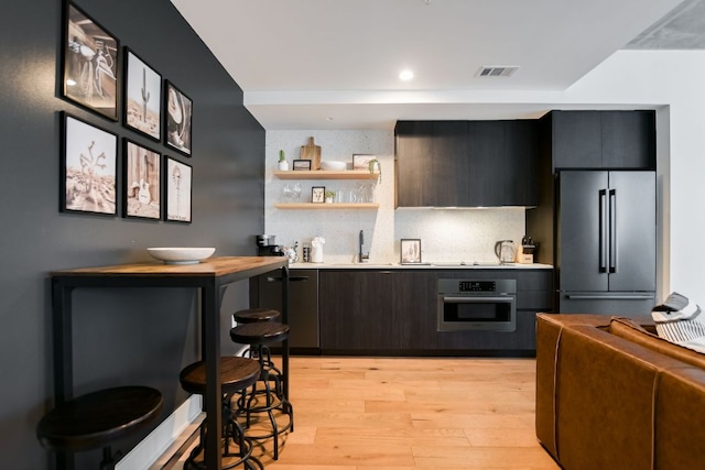 kitchen with visible vents, open shelves, light wood-style floors, light countertops, and stainless steel appliances