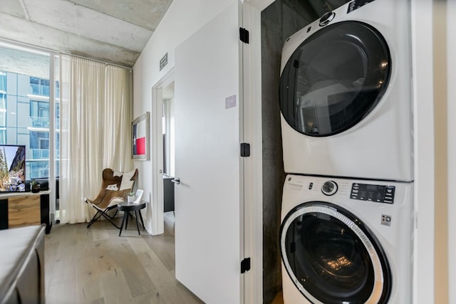 clothes washing area featuring laundry area, light wood finished floors, stacked washer / dryer, and visible vents