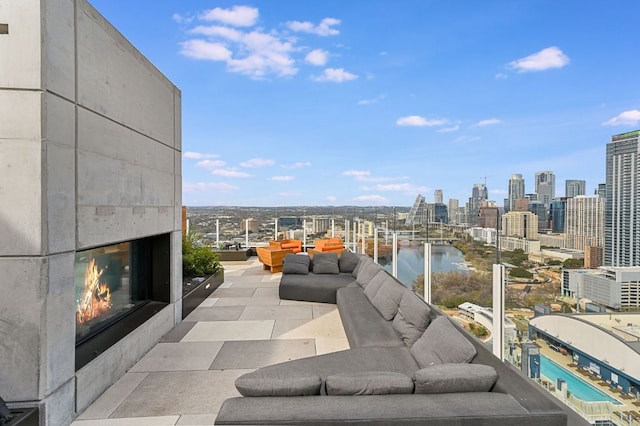 balcony featuring a view of city, an outdoor living space with a fireplace, and a water view