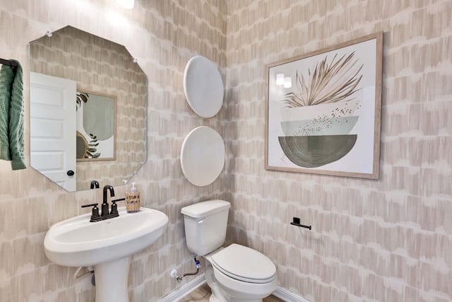 half bath with toilet, tile walls, and a sink