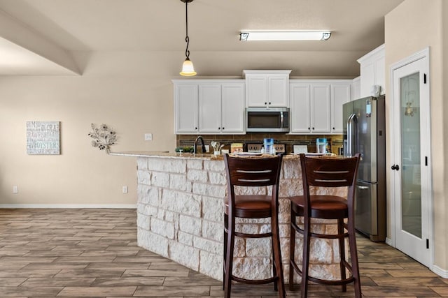 kitchen with stainless steel appliances, baseboards, white cabinetry, dark wood-type flooring, and backsplash