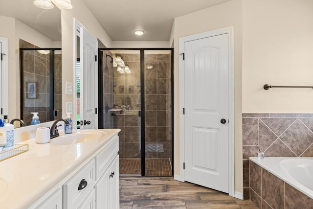 bathroom with vanity, wood finished floors, a garden tub, and a stall shower