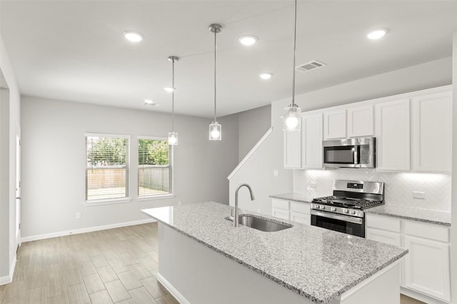 18305 Emu Ln, Manor, TX 78653 - kitchen featuring stainless steel appliances, a sink, decorative backsplash, baseboards, and an island with sink