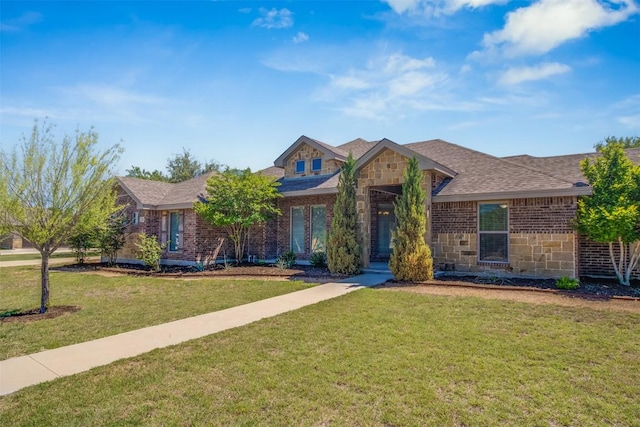 view of front of house with brick siding, a front lawn, roof with shingles, and stone siding