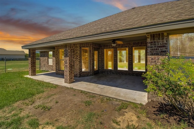 back of property featuring roof with shingles, a ceiling fan, and a patio