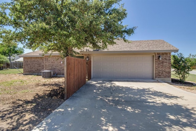 garage featuring fence, central air condition unit, and driveway