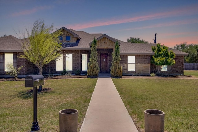 view of front of property with brick siding, a shingled roof, and a front lawn