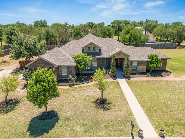 single story home featuring roof with shingles, a front lawn, and brick siding