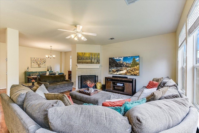living area with a fireplace, ceiling fan with notable chandelier, wood finished floors, and visible vents