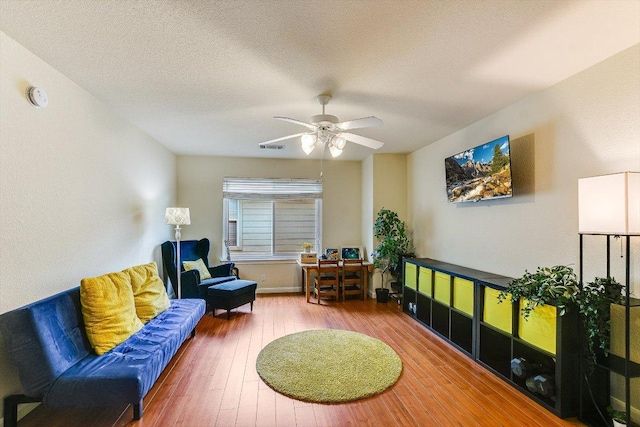 sitting room featuring wood-type flooring, a ceiling fan, a textured ceiling, and visible vents