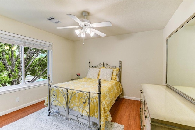 bedroom featuring baseboards, ceiling fan, wood finished floors, and visible vents