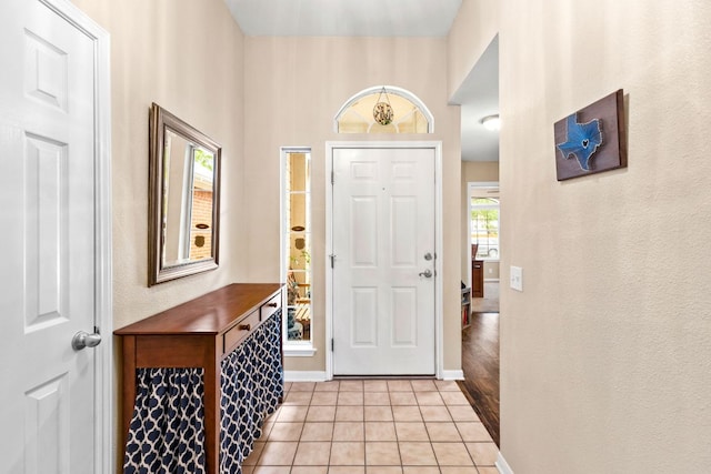 entrance foyer featuring baseboards, a textured wall, and light tile patterned flooring