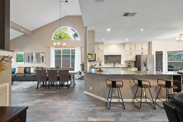 kitchen featuring visible vents, open floor plan, a kitchen bar, appliances with stainless steel finishes, and a notable chandelier