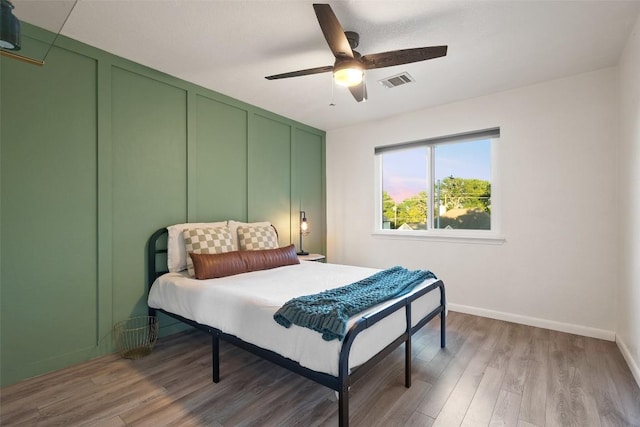 bedroom featuring a ceiling fan, baseboards, visible vents, and light wood-style flooring