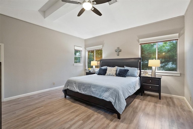 bedroom with baseboards, lofted ceiling with beams, multiple windows, and wood finished floors