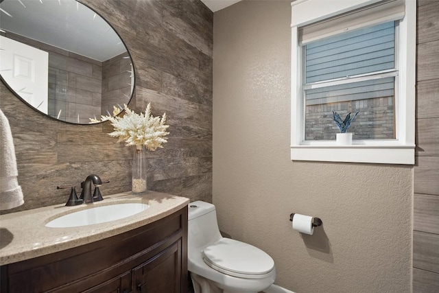 bathroom with toilet, a textured wall, and vanity