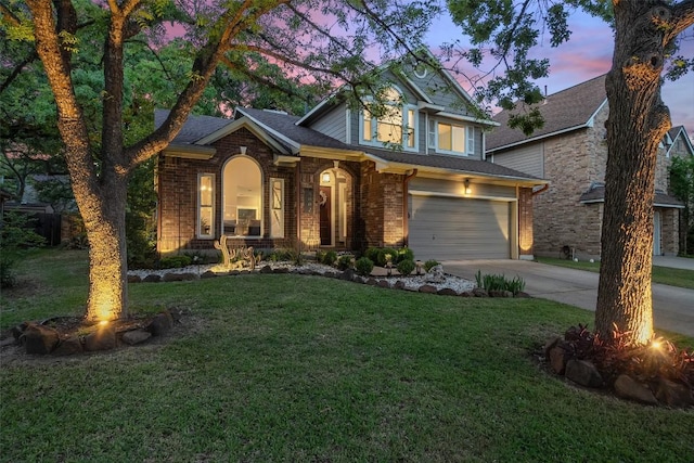 view of front of property with a lawn, an attached garage, driveway, and brick siding