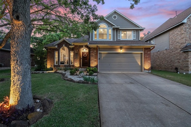 traditional home with brick siding, a garage, a yard, and driveway