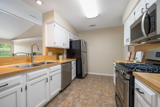 kitchen featuring wooden counters, white cabinetry, tasteful backsplash, a sink, and appliances with stainless steel finishes