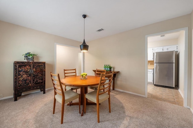 dining area with baseboards, visible vents, and light colored carpet