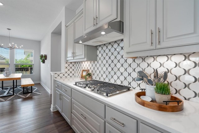 225 Palio Pl, Georgetown, TX 78628 - kitchen with under cabinet range hood, stainless steel gas stovetop, dark wood-type flooring, light countertops, and tasteful backsplash
