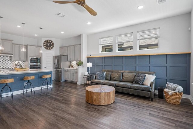 living area featuring ceiling fan, visible vents, dark wood-style floors, a decorative wall, and recessed lighting
