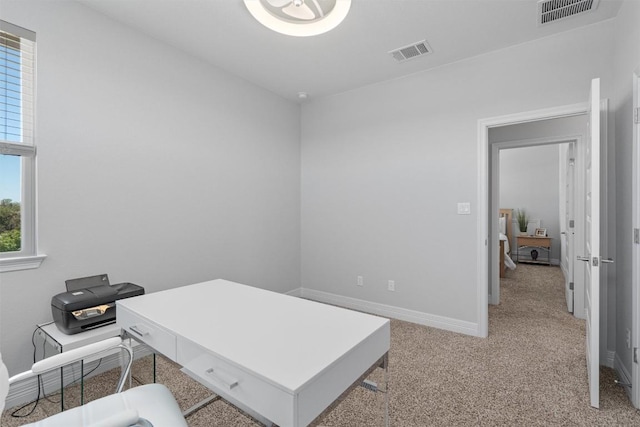 office featuring baseboards, visible vents, and light carpet