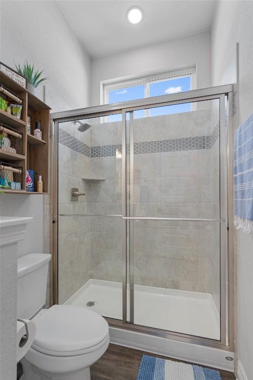 bathroom featuring a stall shower, toilet, and wood finished floors
