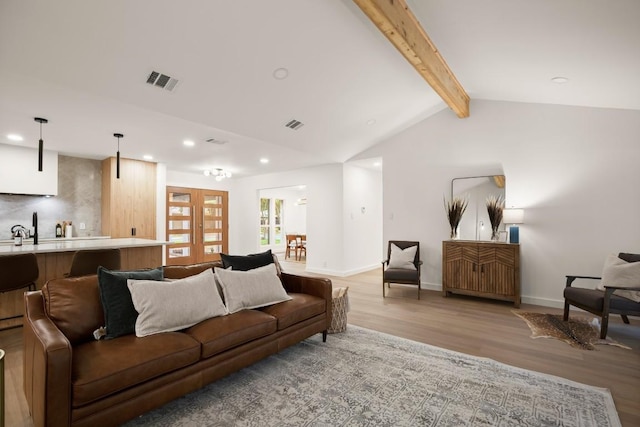 living area featuring recessed lighting, visible vents, vaulted ceiling with beams, and light wood finished floors