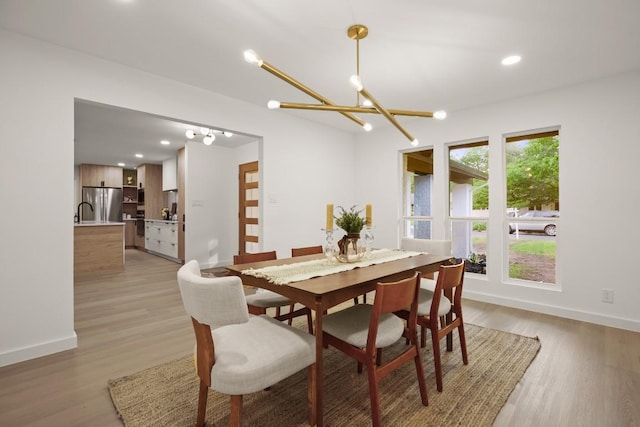 dining area featuring baseboards, an inviting chandelier, and light wood-type flooring
