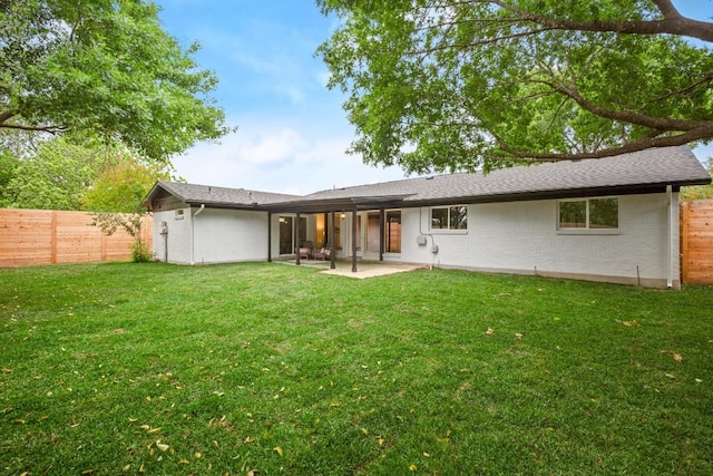 back of property with a yard, a fenced backyard, and a patio area