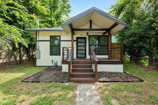 property entrance featuring fence, covered porch, and a yard