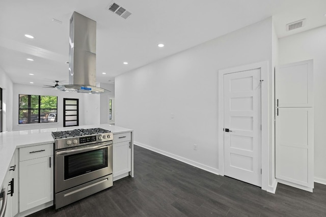 kitchen featuring visible vents, stainless steel gas stove, island range hood, dark wood-type flooring, and white cabinetry