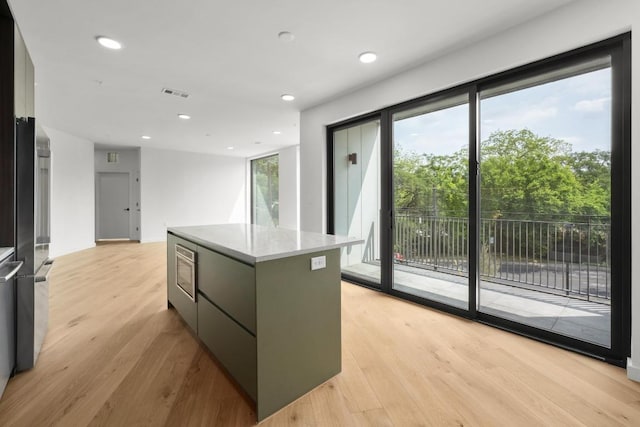 2209 S 1st St Unit 206, Austin, TX 78704 - kitchen with a kitchen island, light wood finished floors, modern cabinets, recessed lighting, and freestanding refrigerator