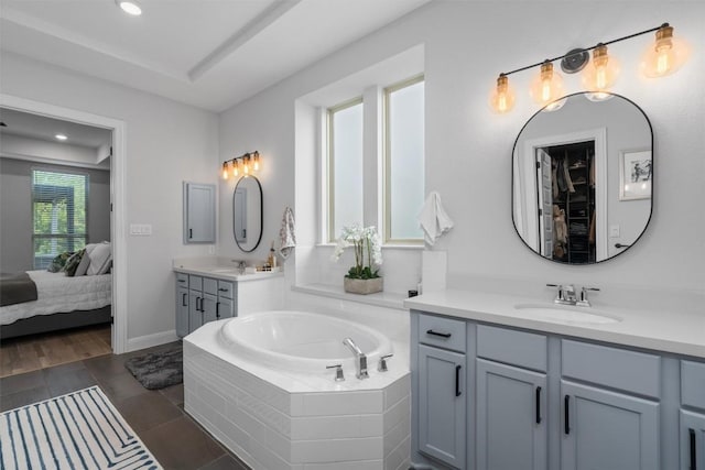 ensuite bathroom featuring ensuite bathroom, two vanities, a sink, and a garden tub