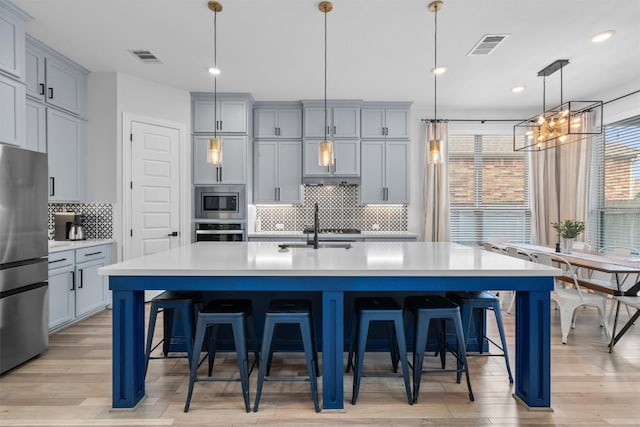 kitchen featuring light wood-style floors, light countertops, tasteful backsplash, and stainless steel appliances