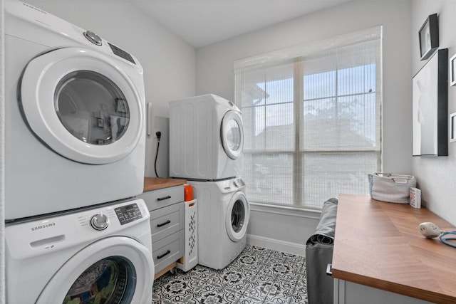 laundry area featuring light tile patterned floors, plenty of natural light, and stacked washer and clothes dryer
