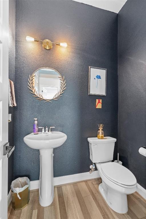 bathroom with baseboards, toilet, and wood finished floors