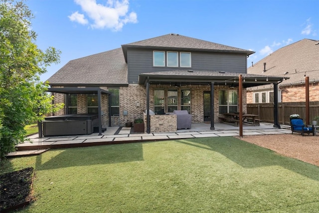 back of property featuring fence, a patio, brick siding, a hot tub, and a yard