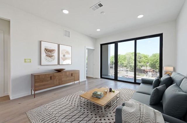 living room featuring baseboards, visible vents, and light wood finished floors